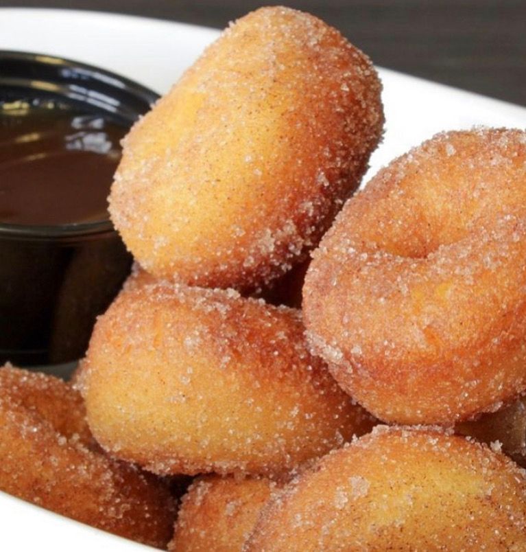 Sugar-coated doughnut holes with chocolate dipping sauce on a plate
