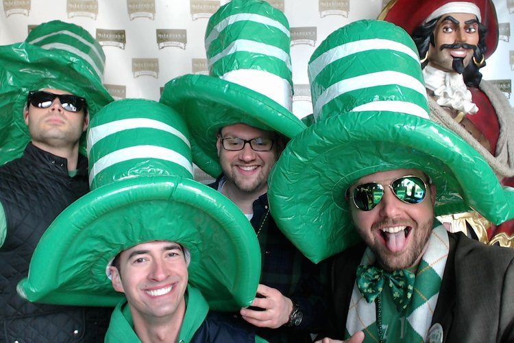 A group of men wearing green hats and sunglasses are posing for a picture.