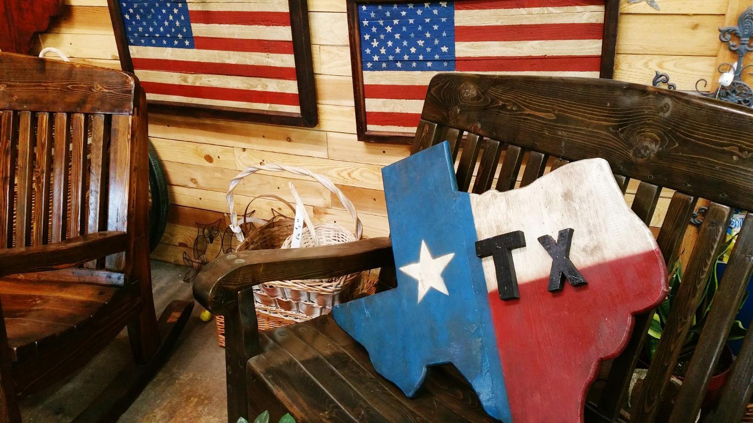 Wooden Texas flag art on a rocking chair, with US flags in the background.