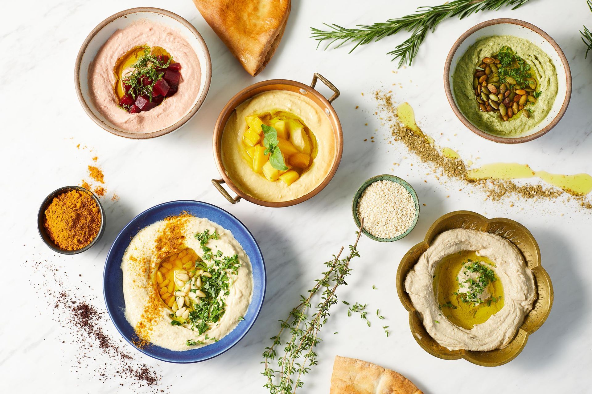 There are many different types of hummus in bowls on the table.
