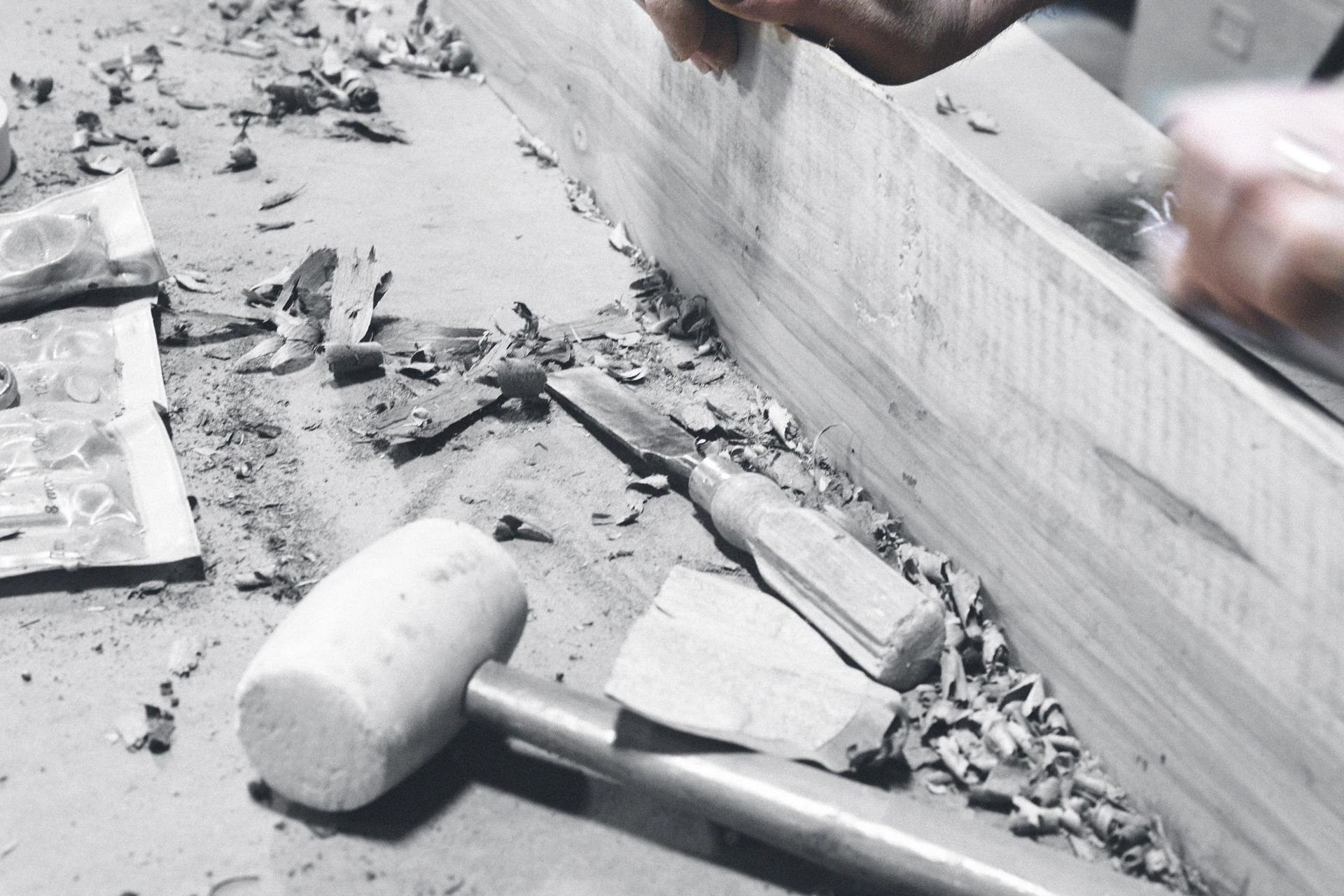 A black and white photo of a person carving a piece of wood
