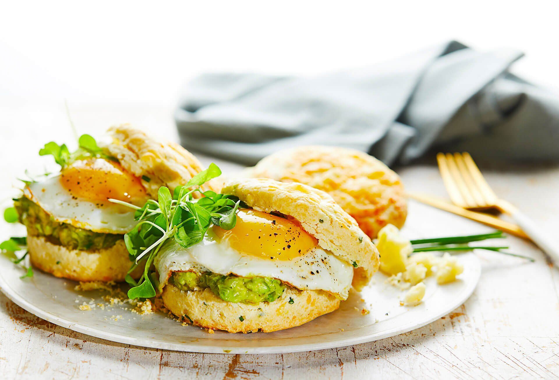 A close up of a plate of food with eggs and avocado on a table.