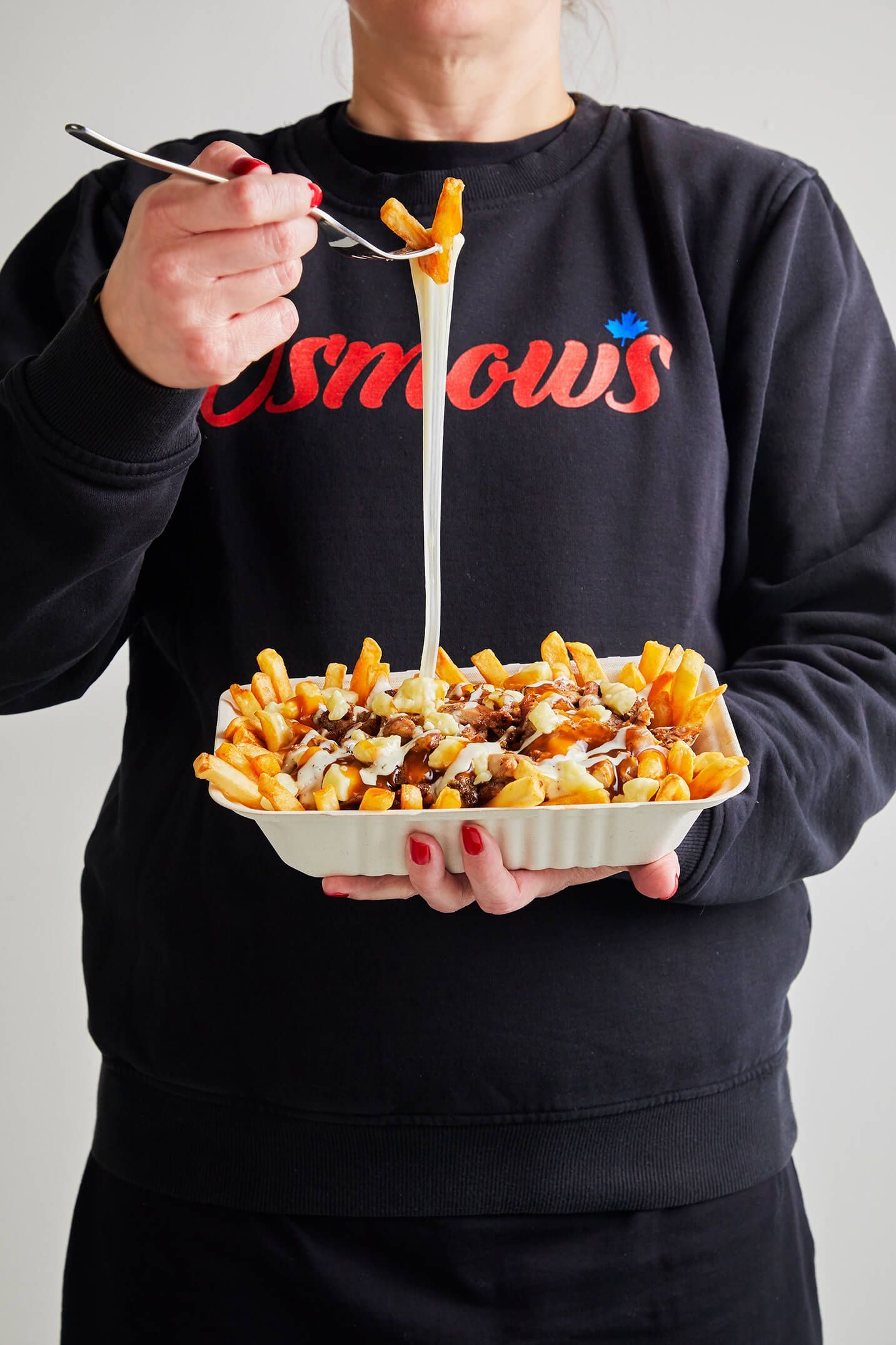 A woman wearing a snows sweatshirt is eating french fries