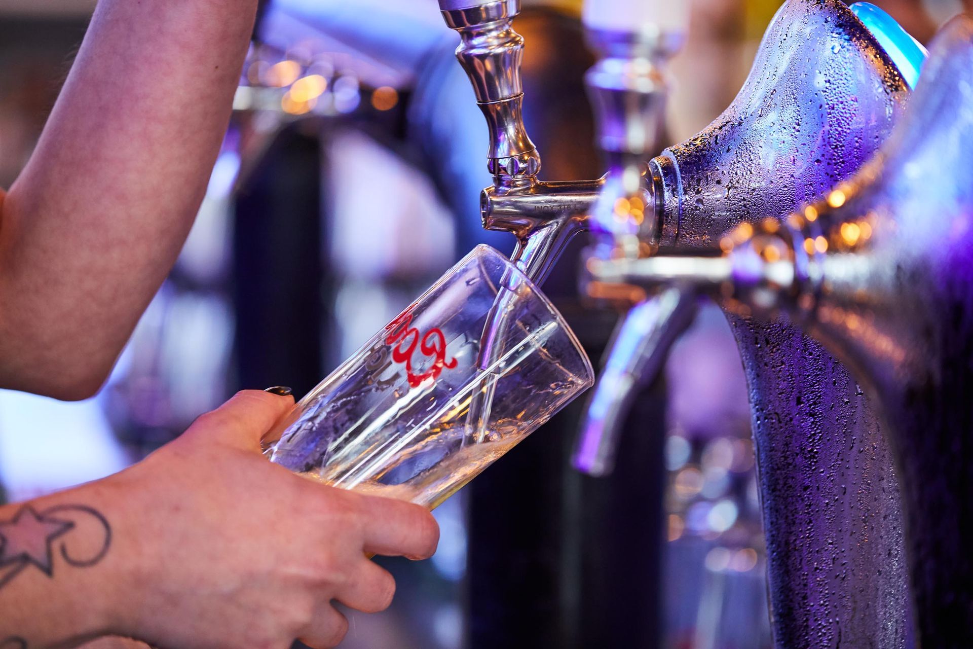 A person is pouring beer into a glass at a bar.