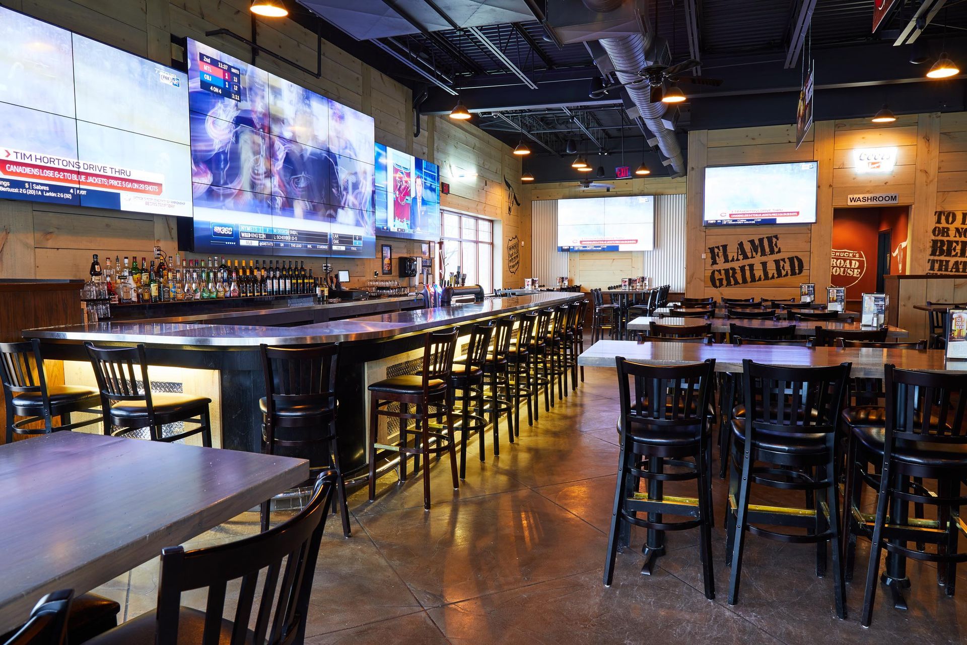A restaurant with tables and chairs and a sign that says flame grilled
