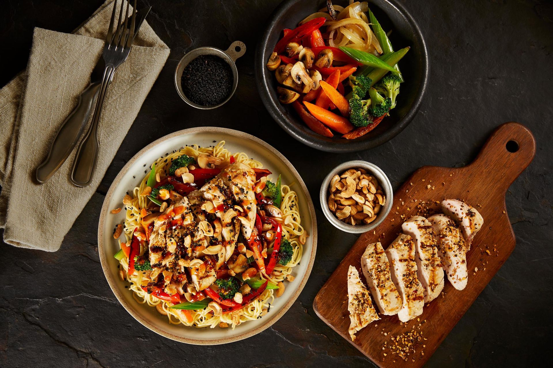 A wooden cutting board with chicken and vegetables on it