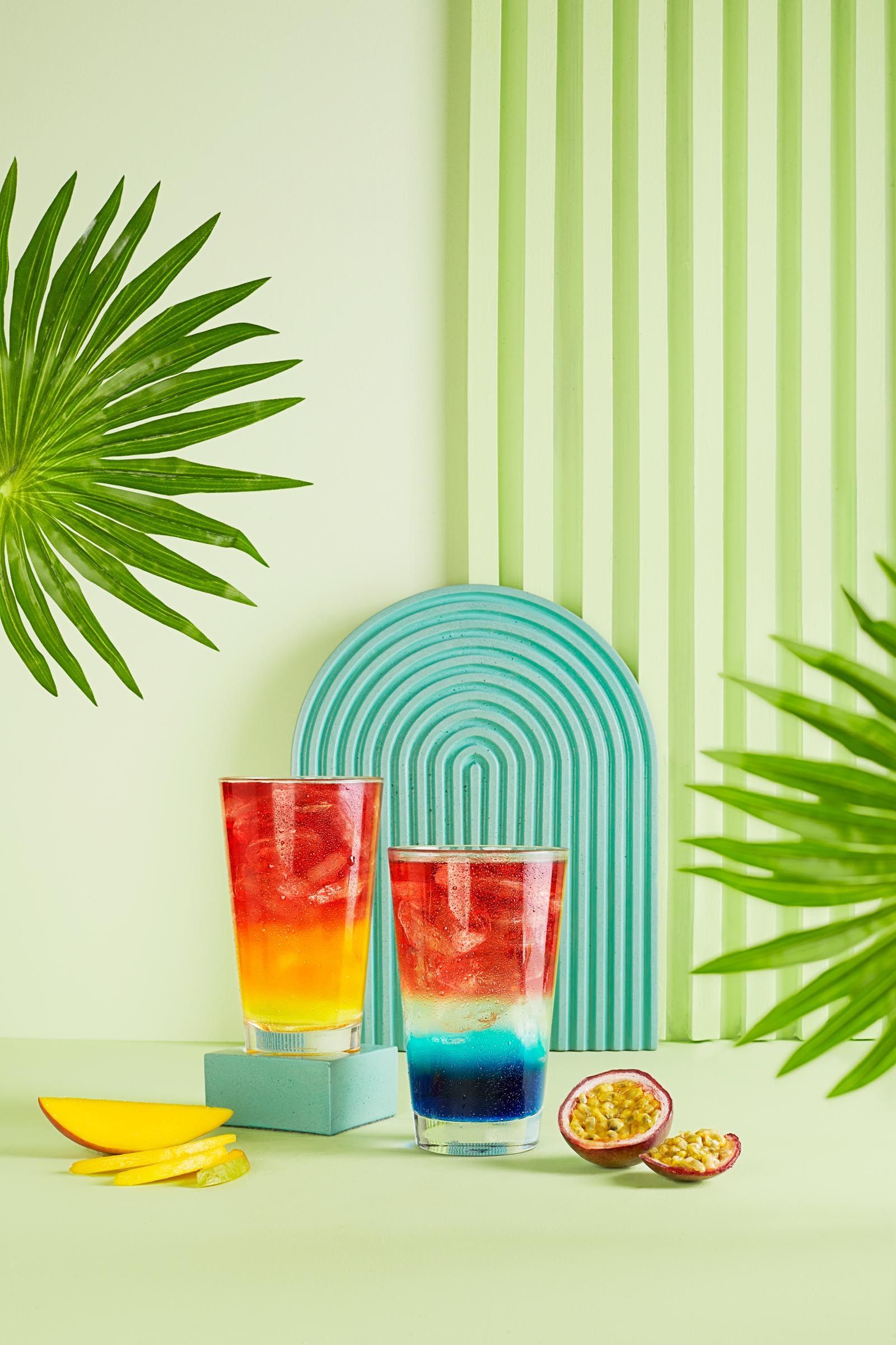 There are two glasses of different colored drinks on the table.