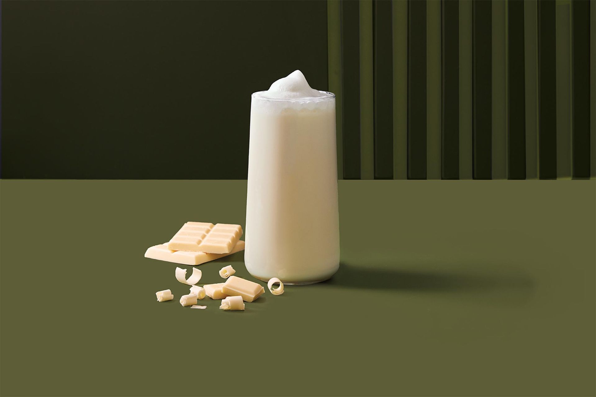 A white chocolate drink is sitting on a table next to a bar of white chocolate.