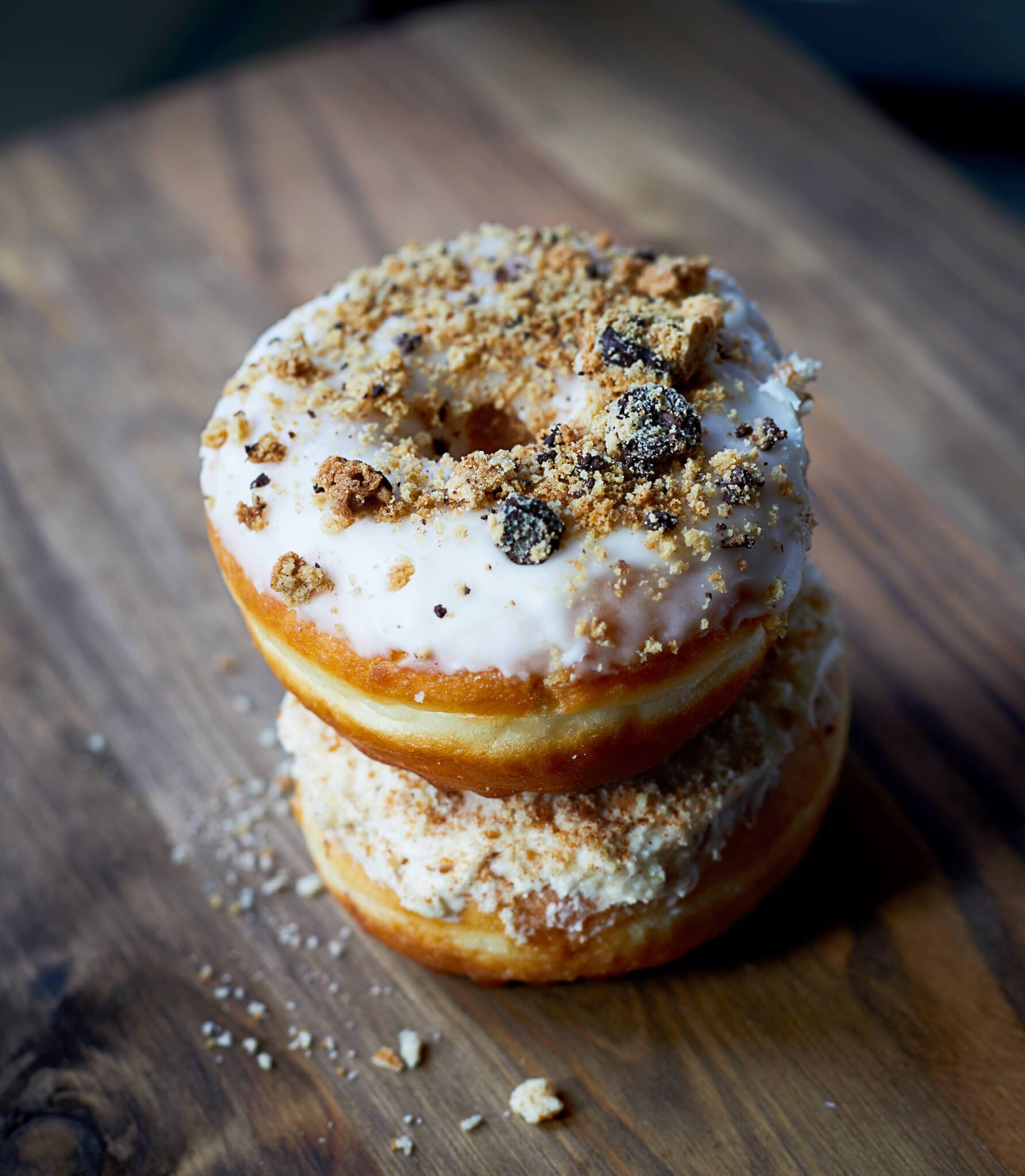 Two donuts stacked on top of each other on a wooden table.