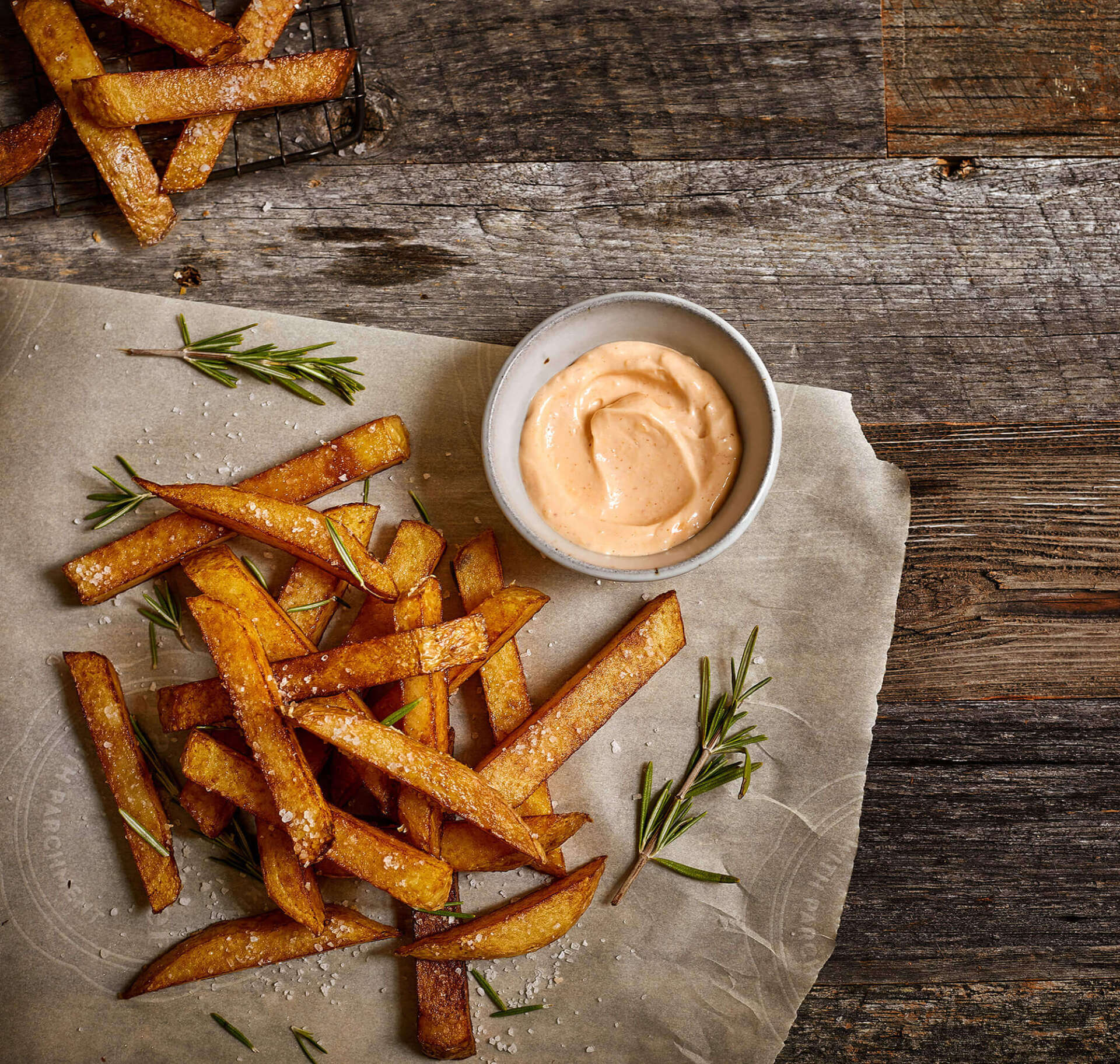 French fries and a bowl of dipping sauce on a wooden table