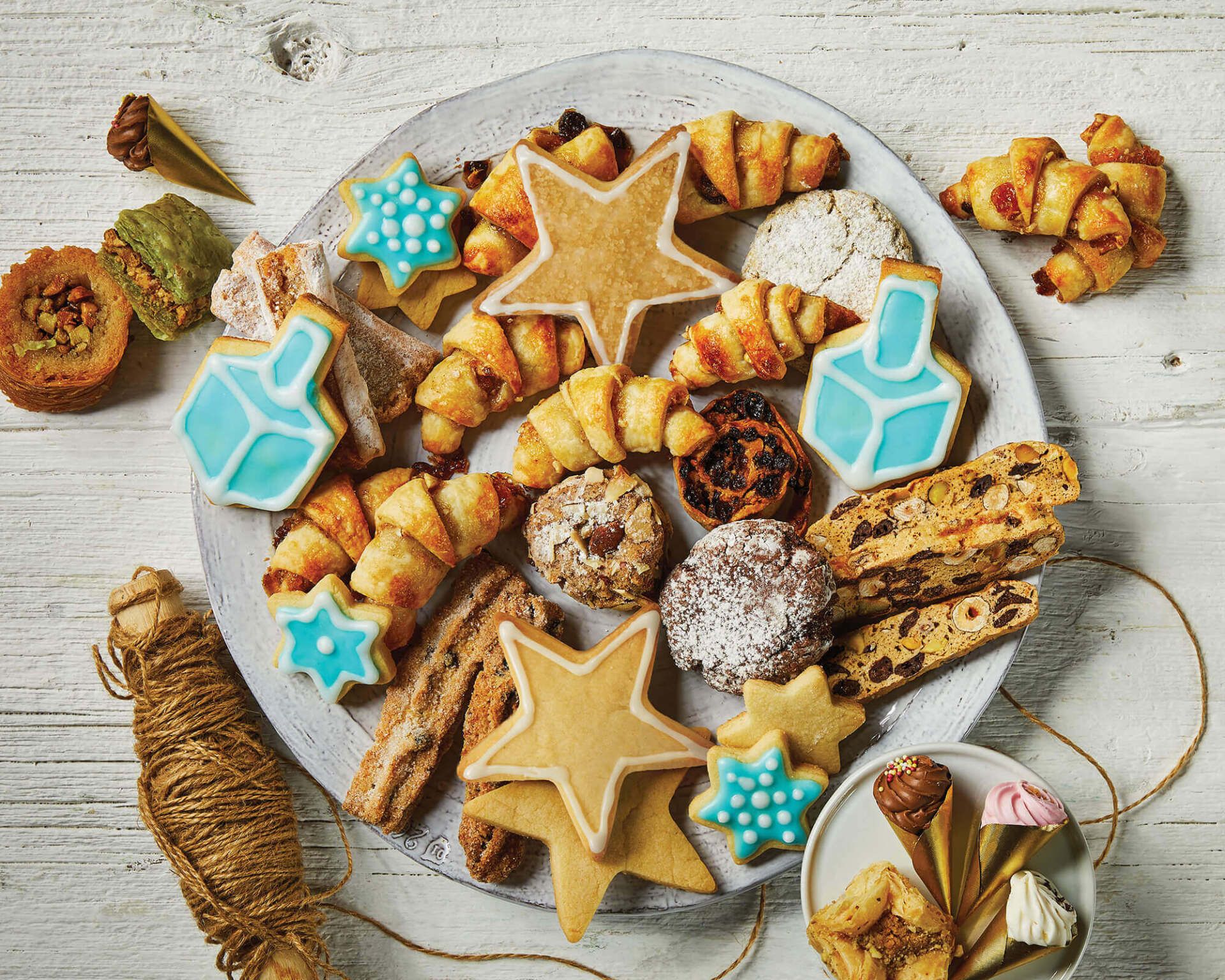 A white plate topped with a variety of cookies on a wooden table.