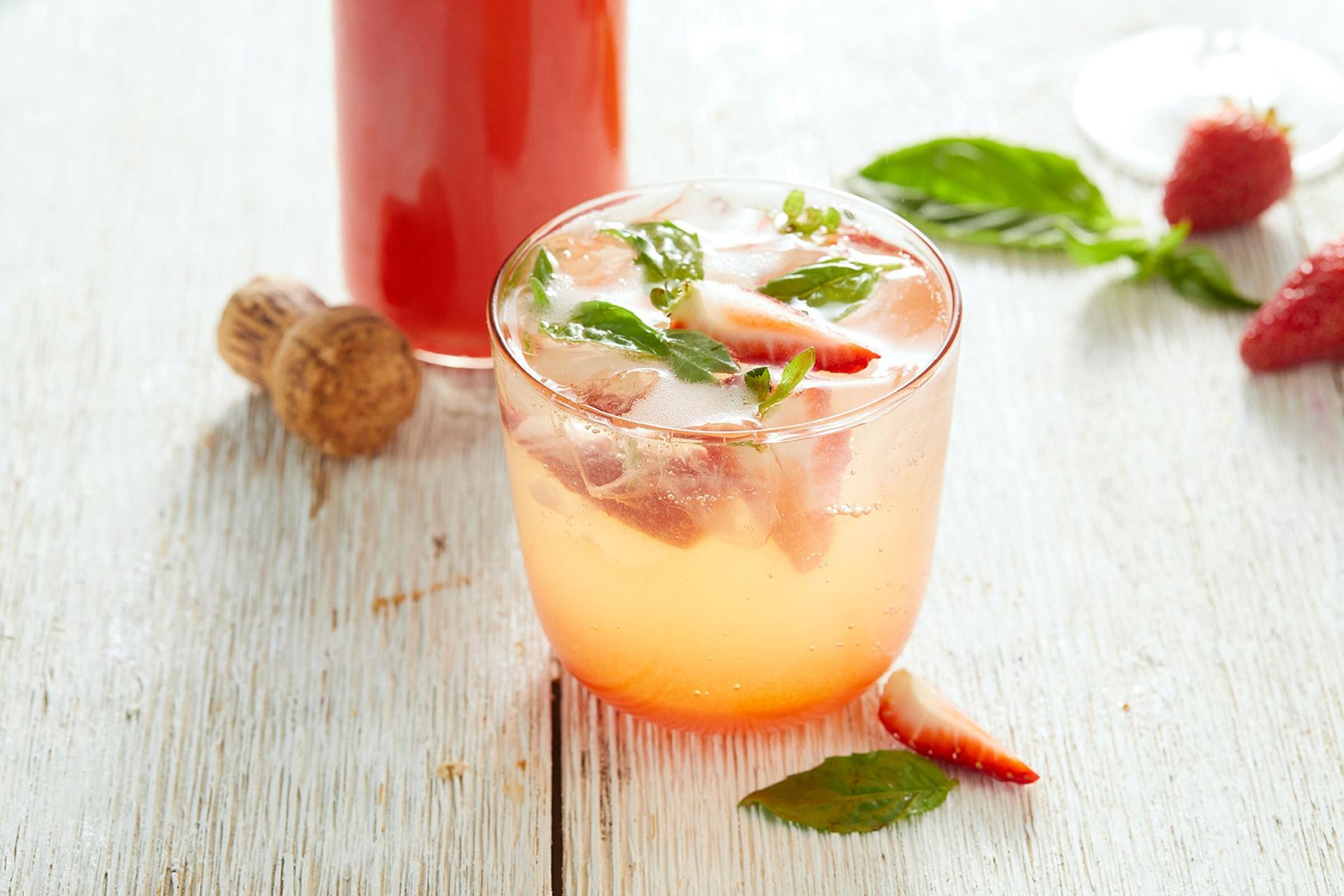 A close up of a strawberry drink in a glass on a table.