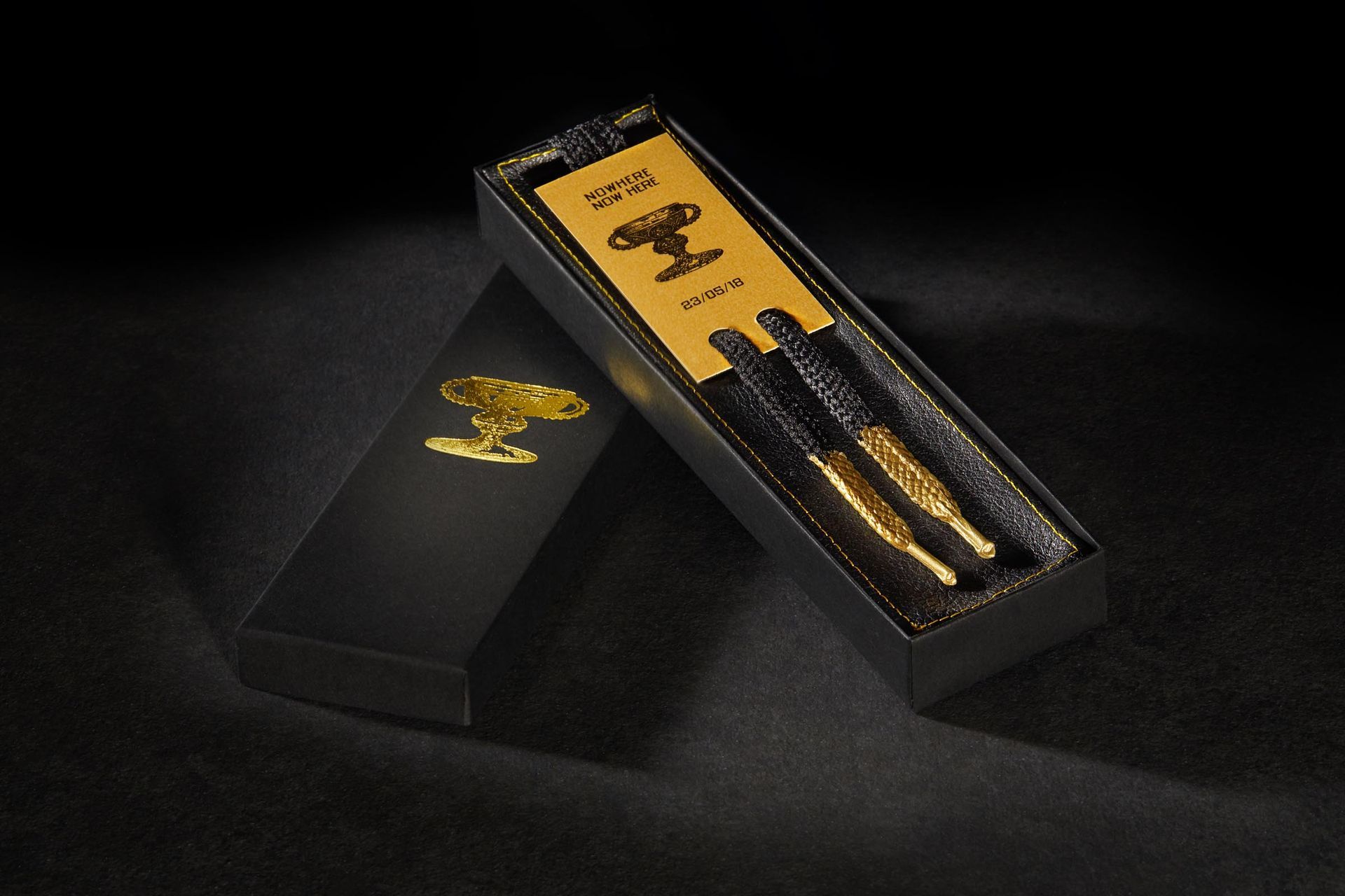 A black box with two gold shoe laces in it