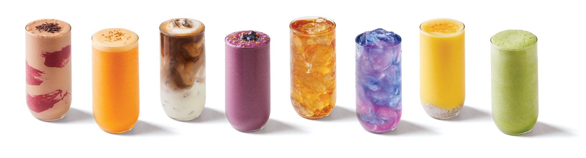 A row of different colored iced drinks are lined up in a row on a white background.