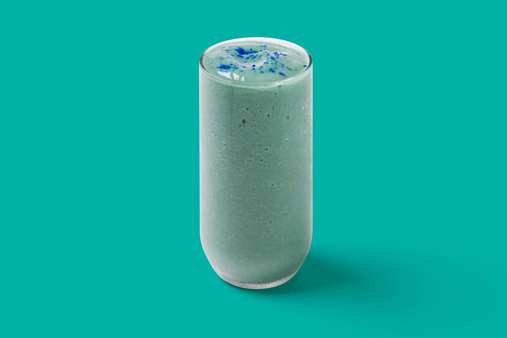 A smoothie in a tall glass on a blue background.