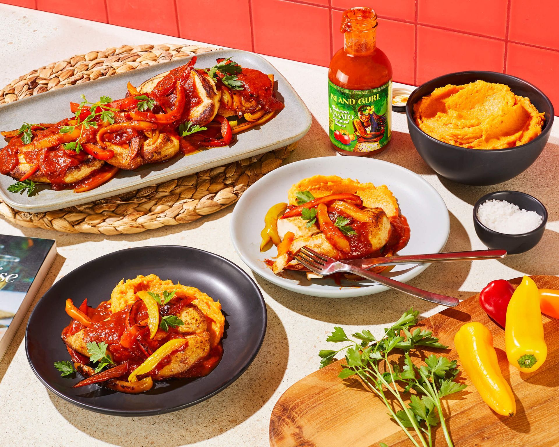 A table topped with plates of food and a bottle of hot sauce.