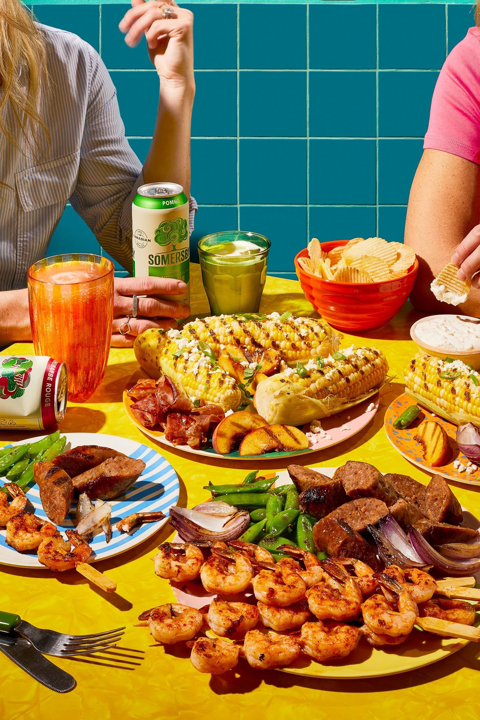 A group of people are sitting at a table with plates of food and drinks.