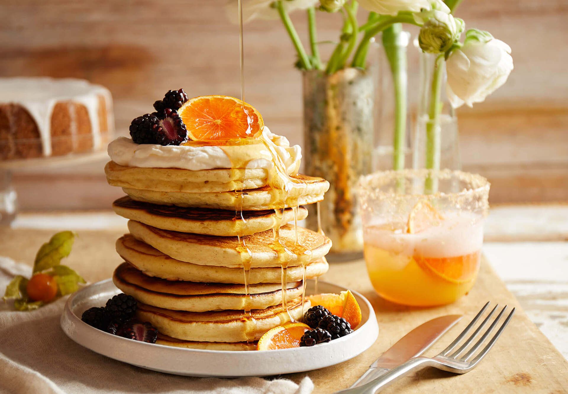 A stack of pancakes with berries and syrup on a plate.