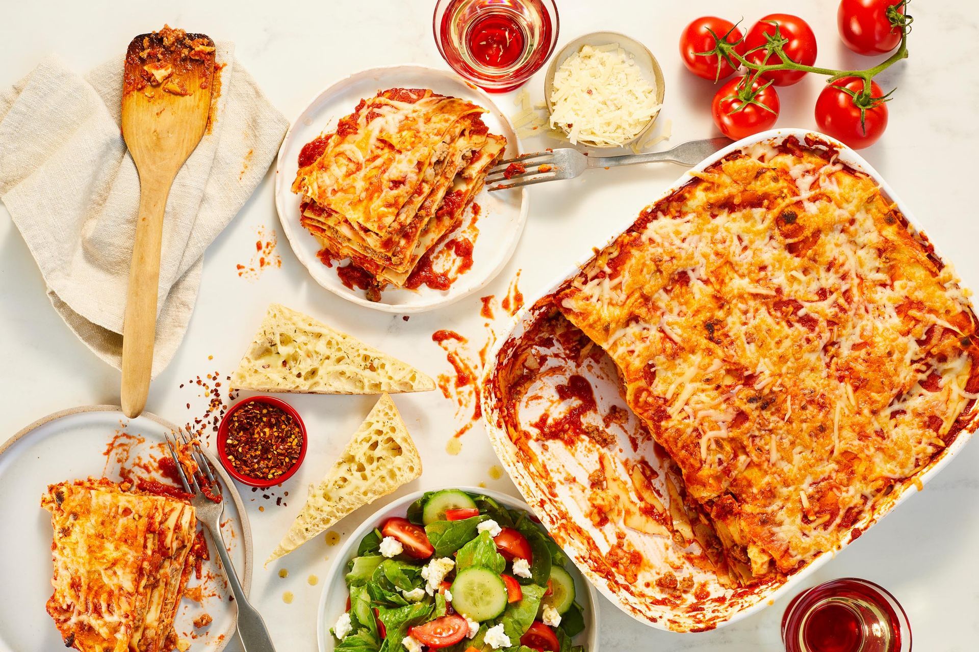 A table topped with plates of food and a casserole dish of lasagna.
