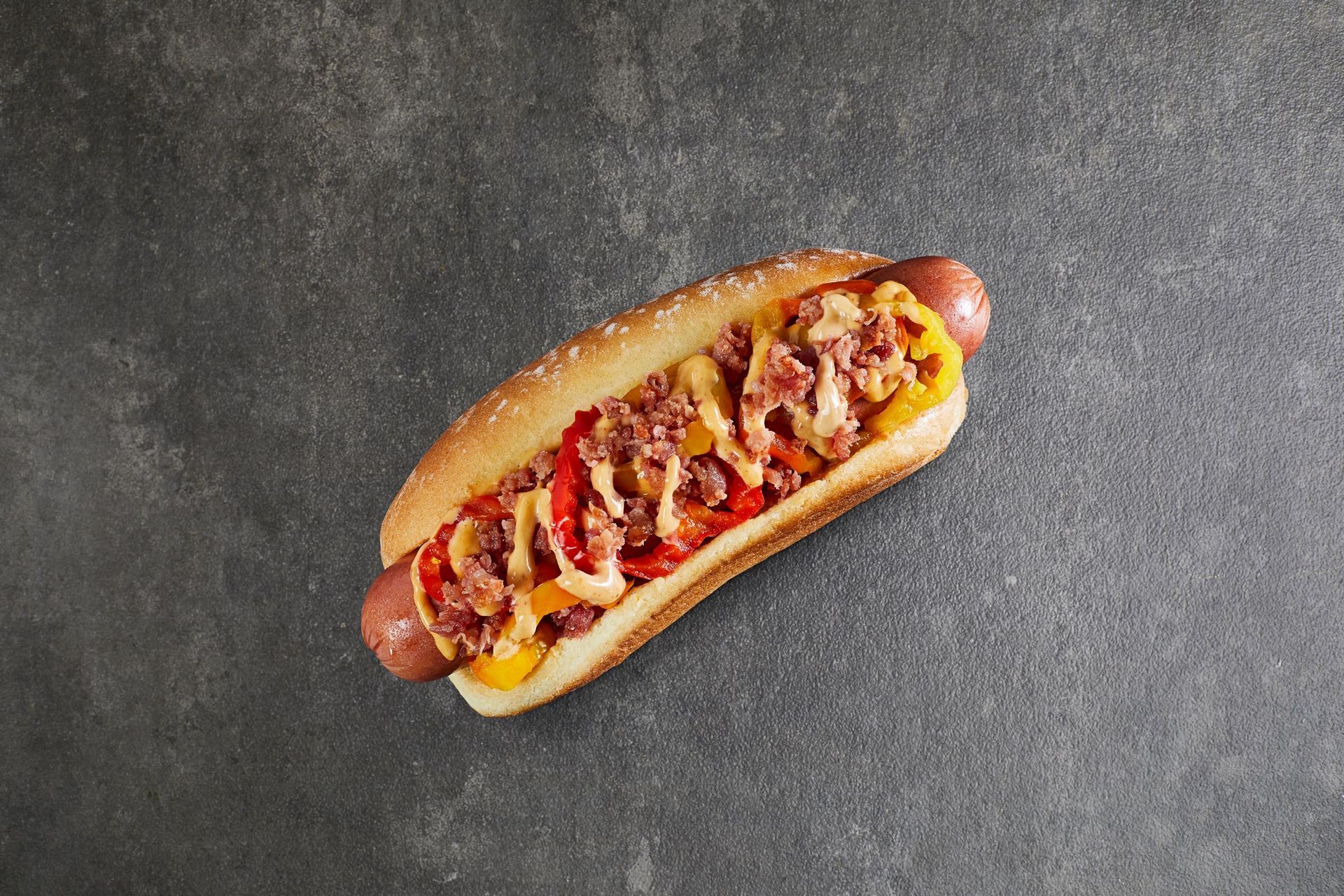 A hot dog with ketchup and mustard on a bun on a table.