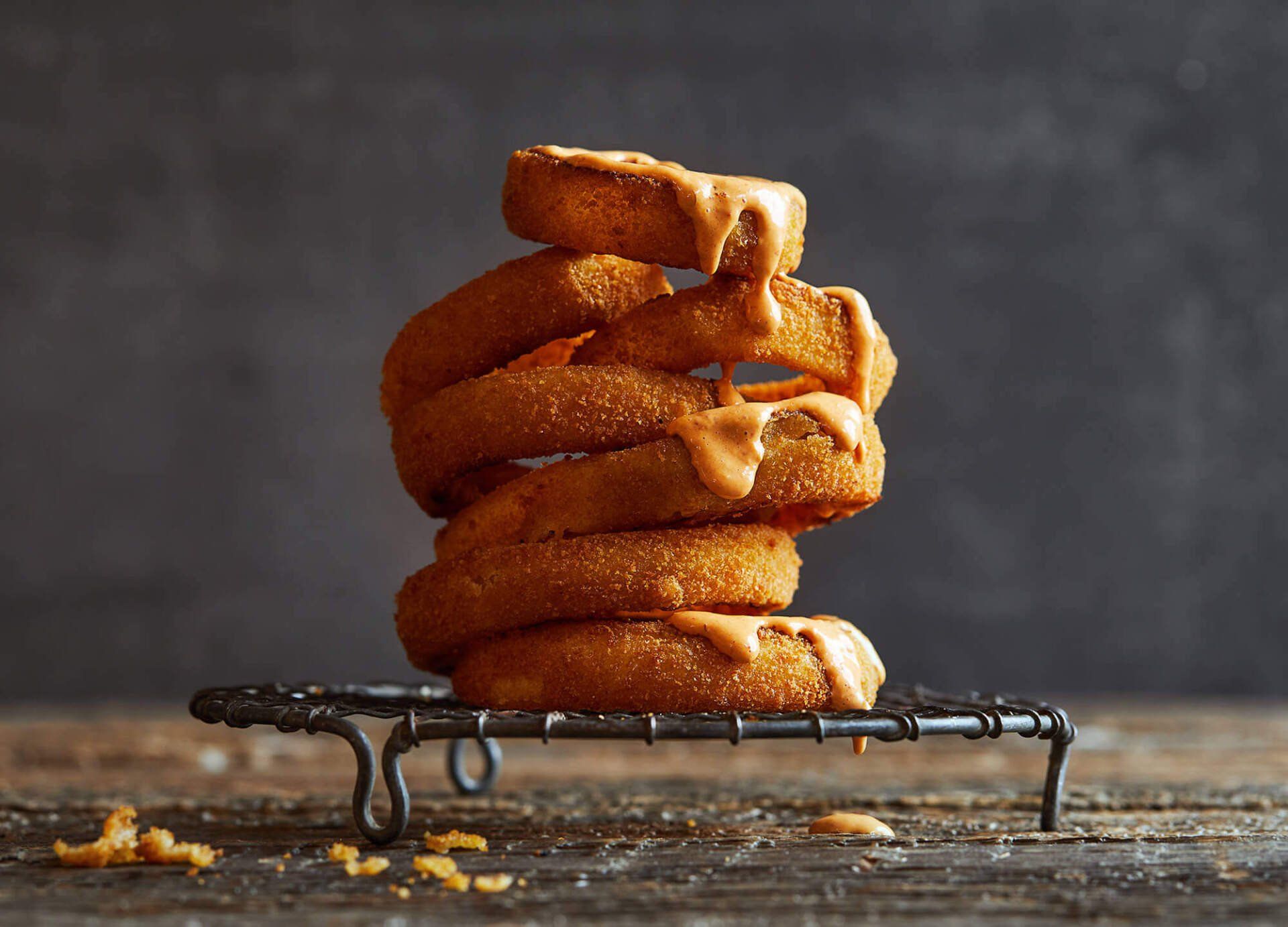 A stack of onion rings on a wire rack on a wooden table.