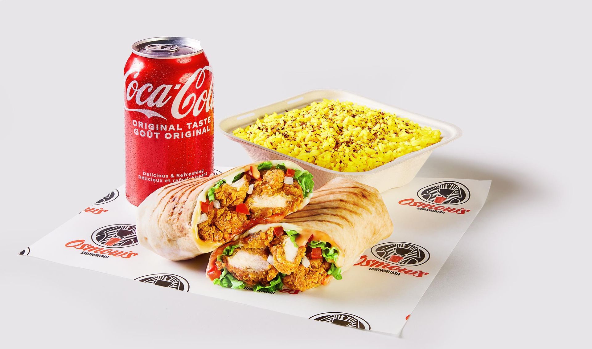 A can of coca cola is next to a plate of food.