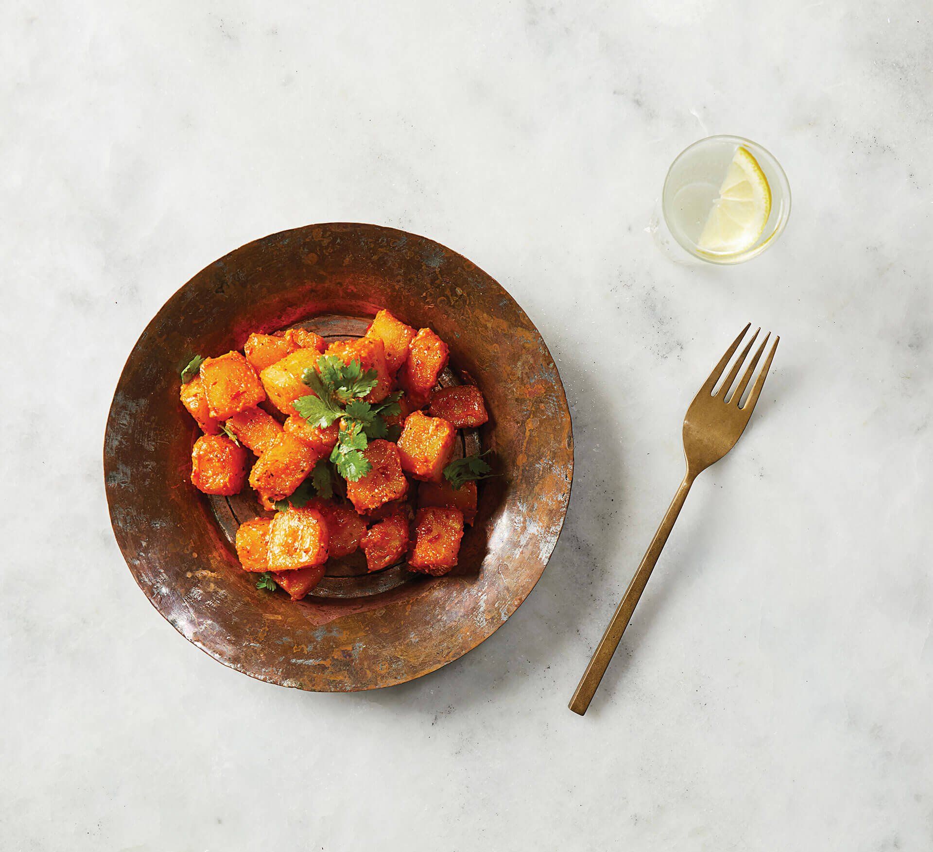 A bowl of food with a fork next to it on a table.