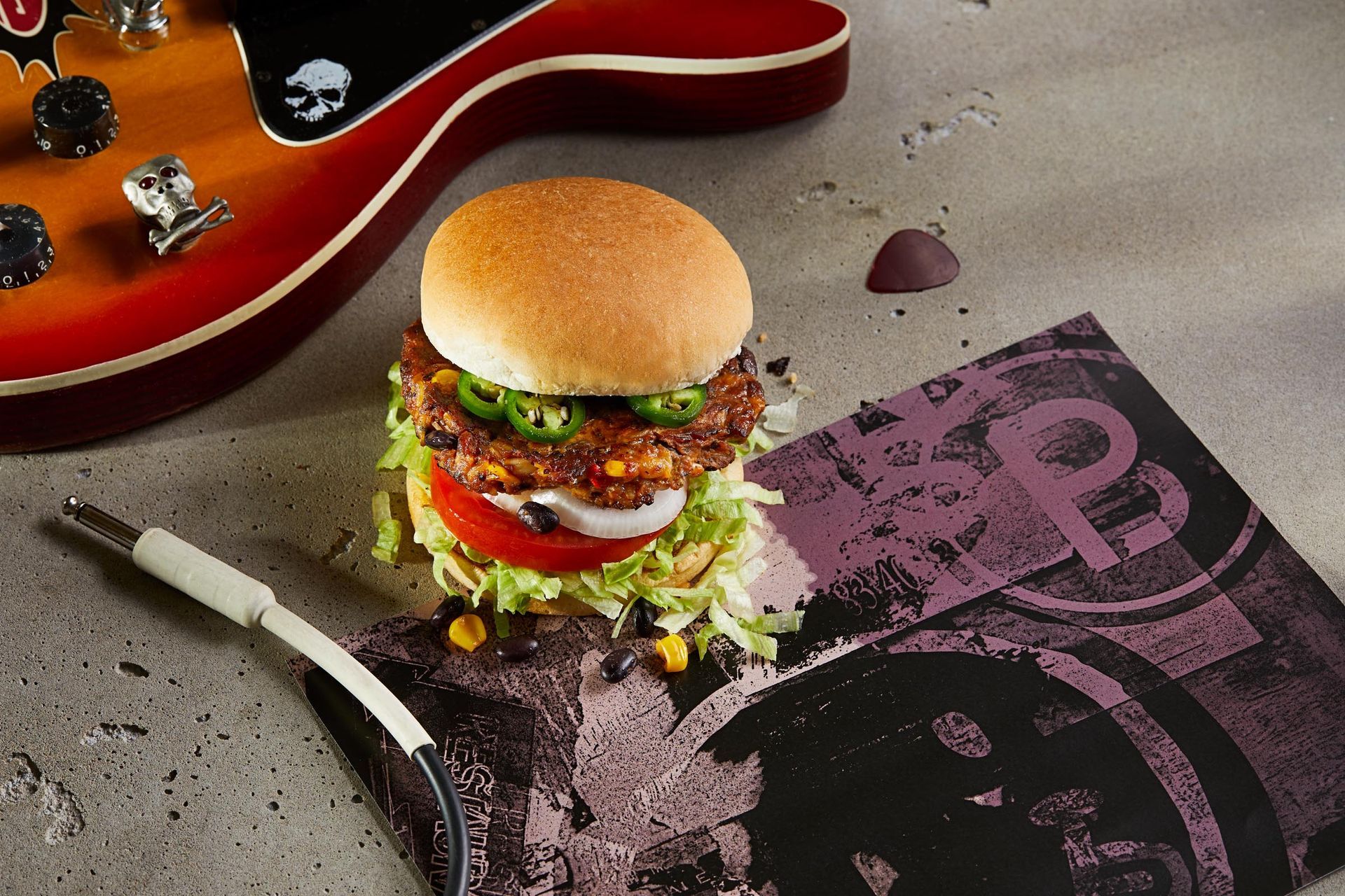 A hamburger is sitting on a napkin next to a guitar