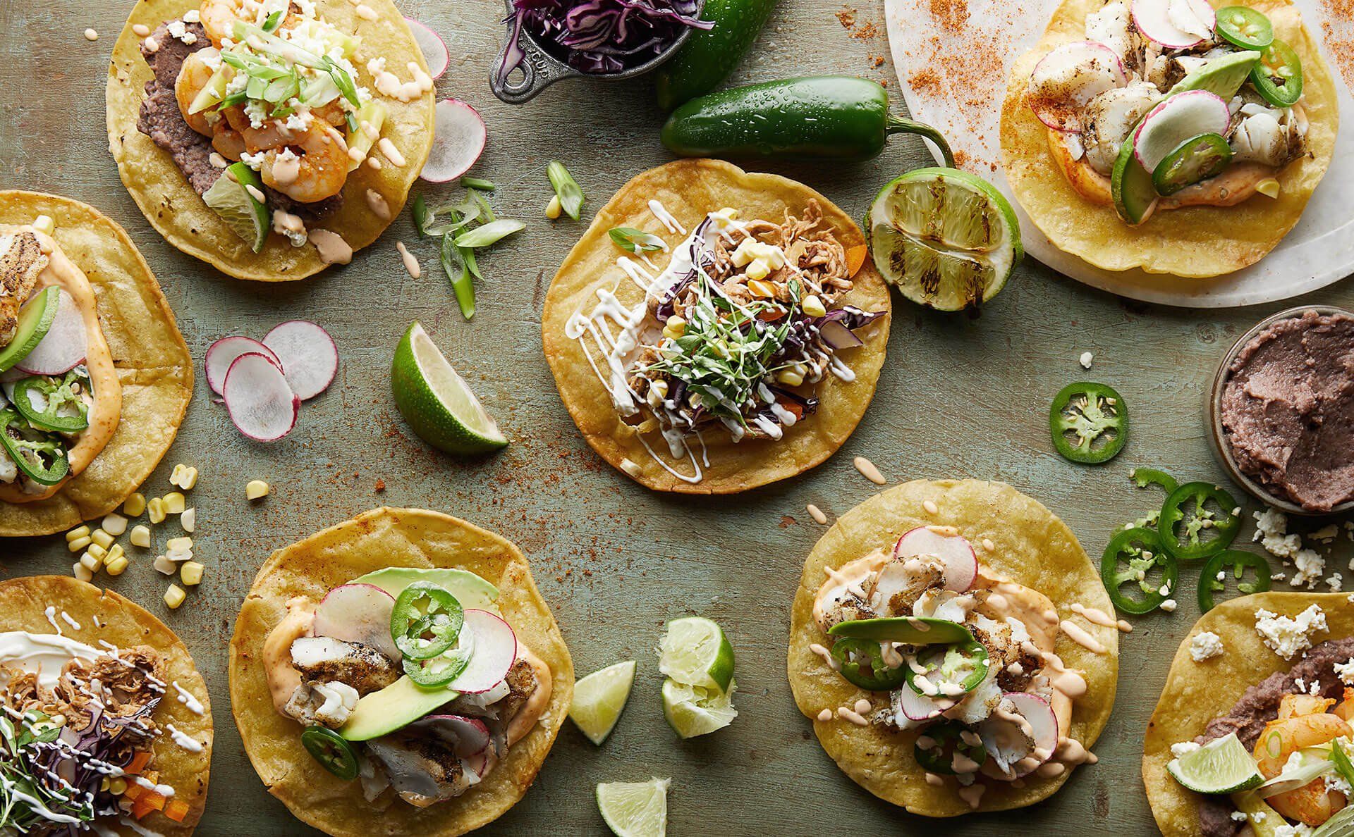 There are many different types of tacos on the table.