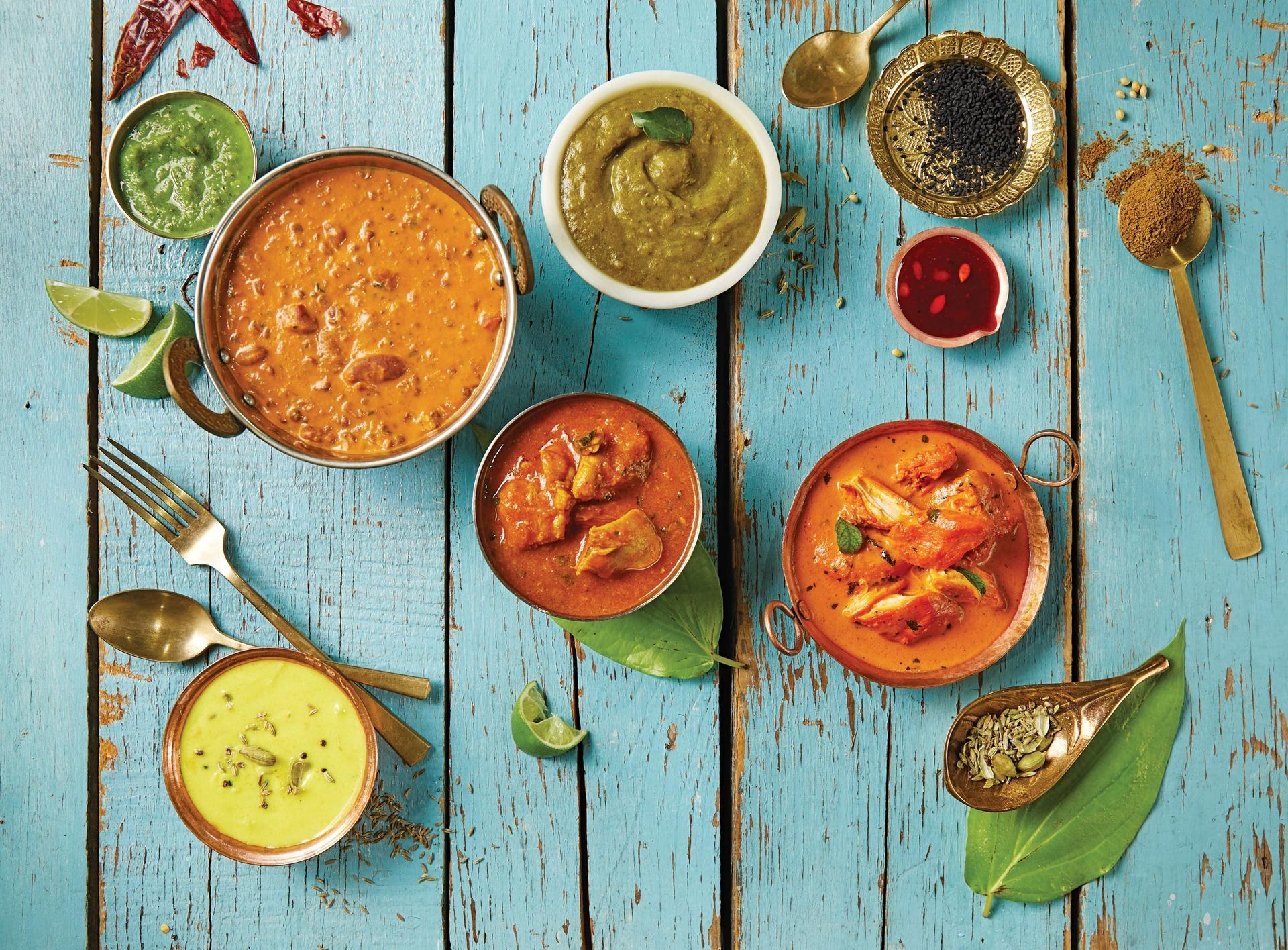 A wooden table topped with bowls of food and spices