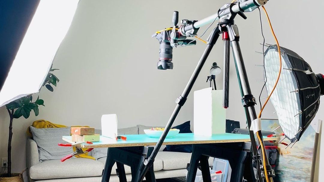 A camera on a tripod is sitting on top of a table in a photo studio.