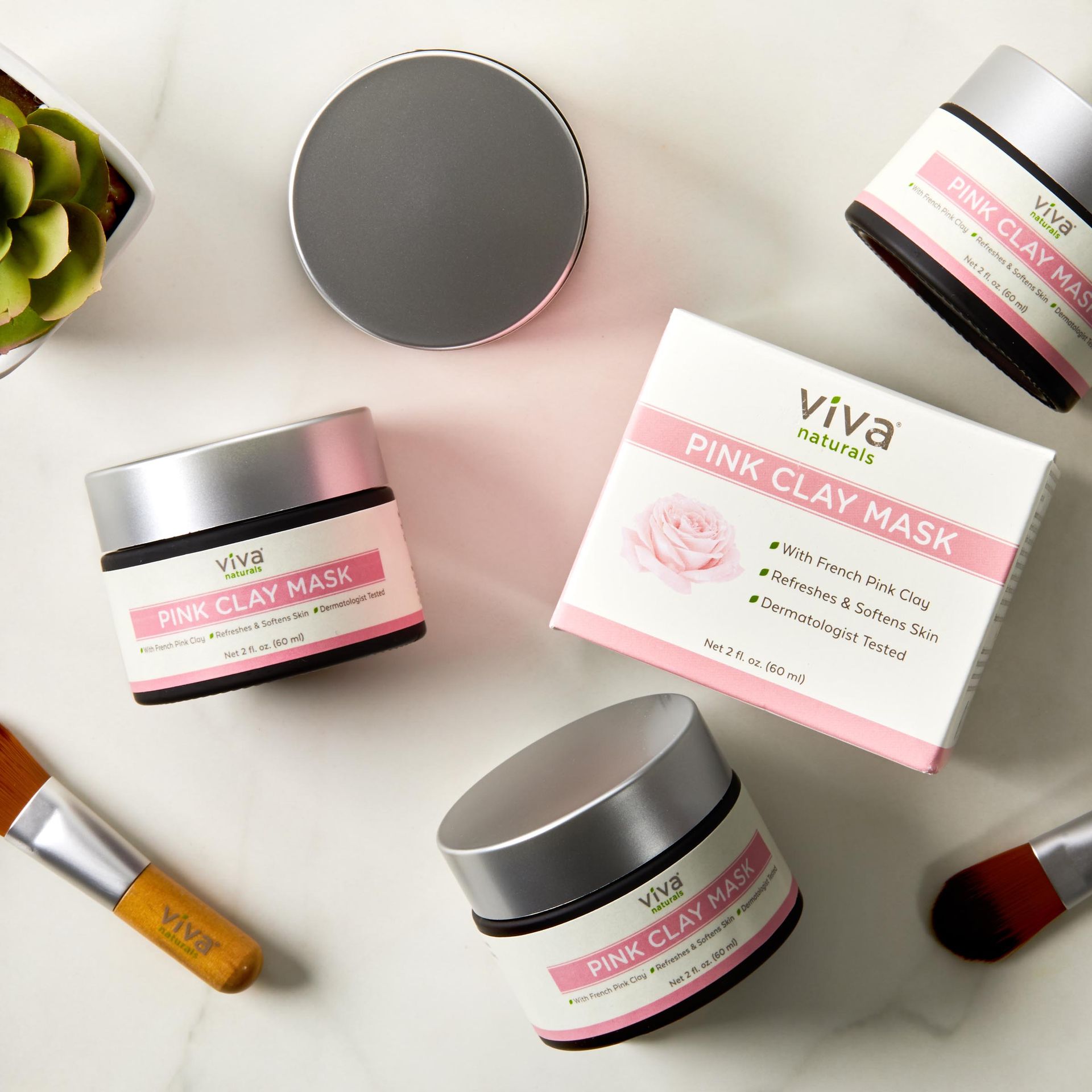 Several jars of pink clay mask are sitting on a table