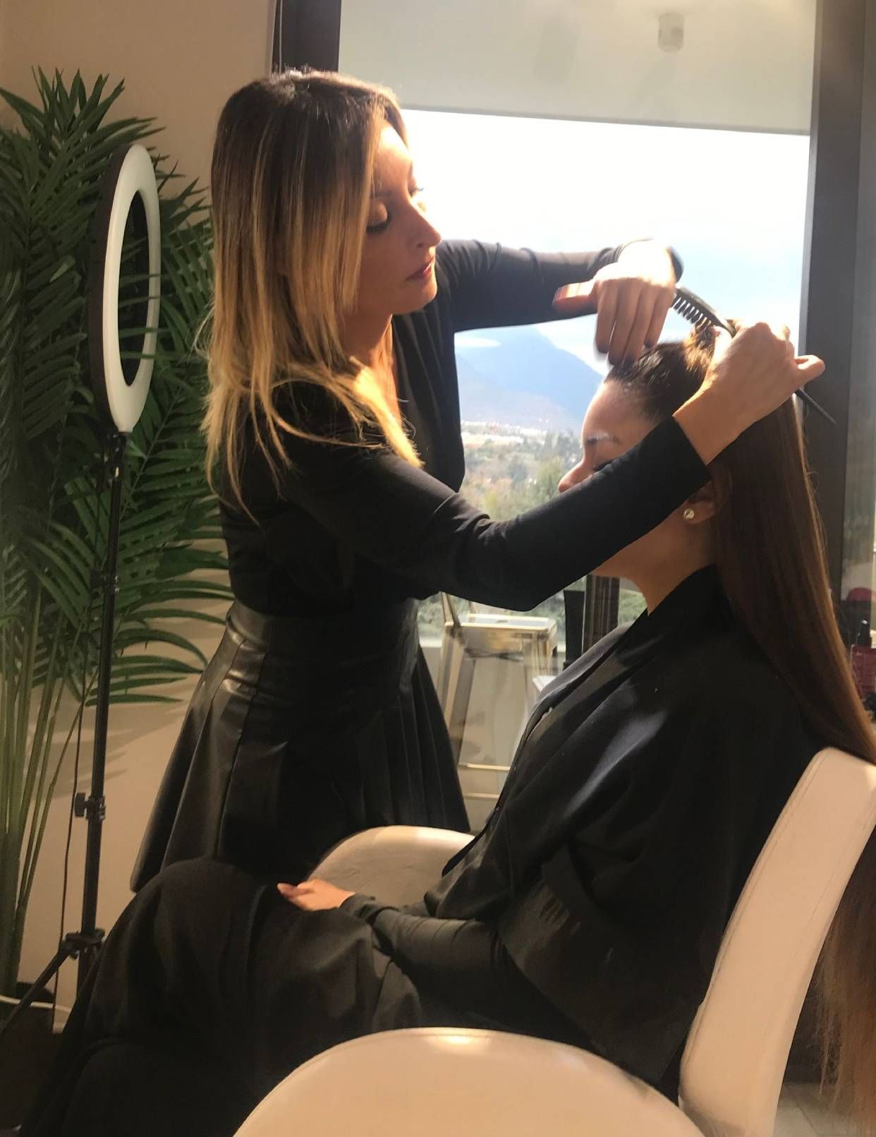 Una mujer está cortando el pelo a otra mujer en un salón.