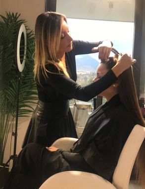 Una mujer está cortando el pelo a otra mujer en un salón.