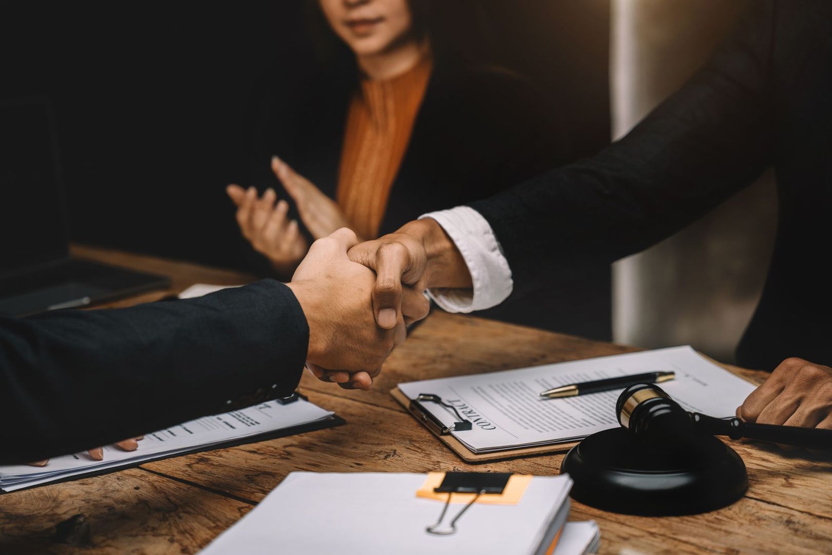 A man and a woman are shaking hands over a table.