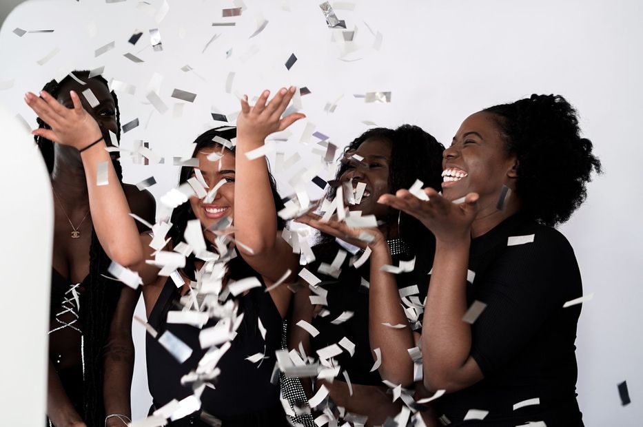 A group of women are throwing confetti in the air.