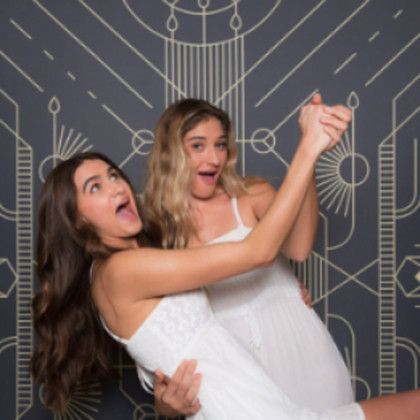 Two women in white dresses are posing for a picture