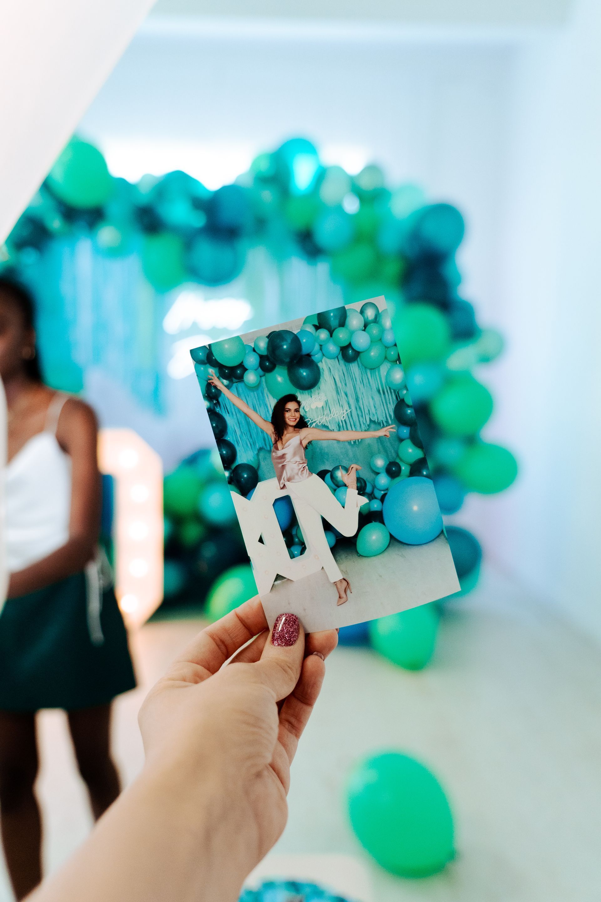 A person is holding a picture of a woman in front of balloons
