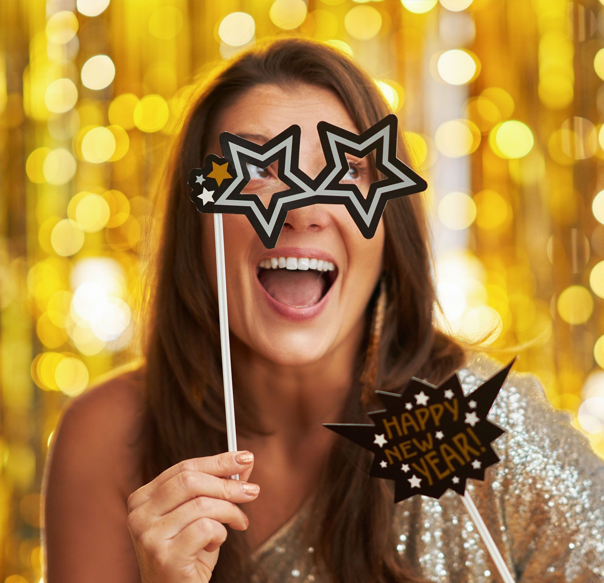 A woman is wearing a pair of star shaped glasses and holding a sign that says happy new year