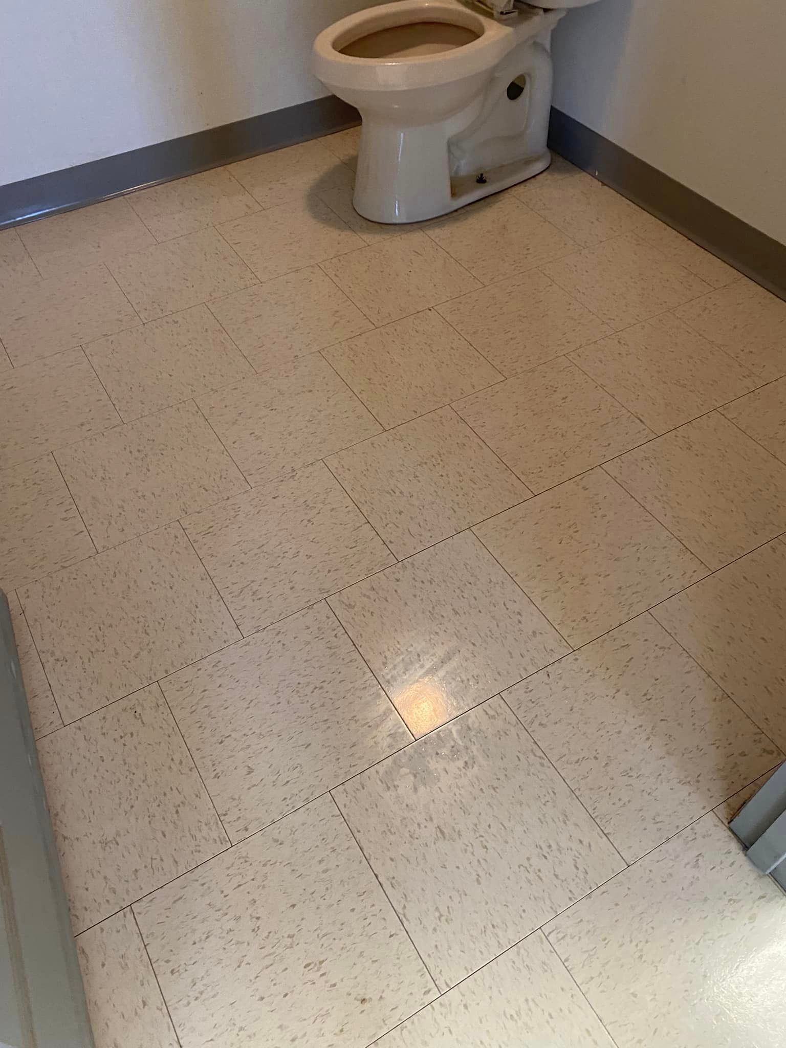 A toilet is sitting on a tiled floor in a bathroom.