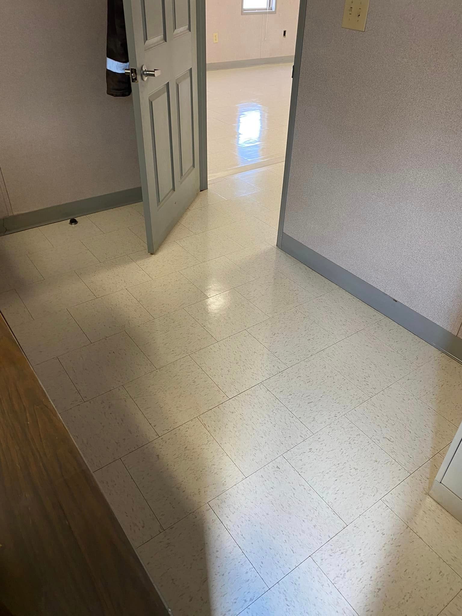 A hallway with a white tile floor and a door.