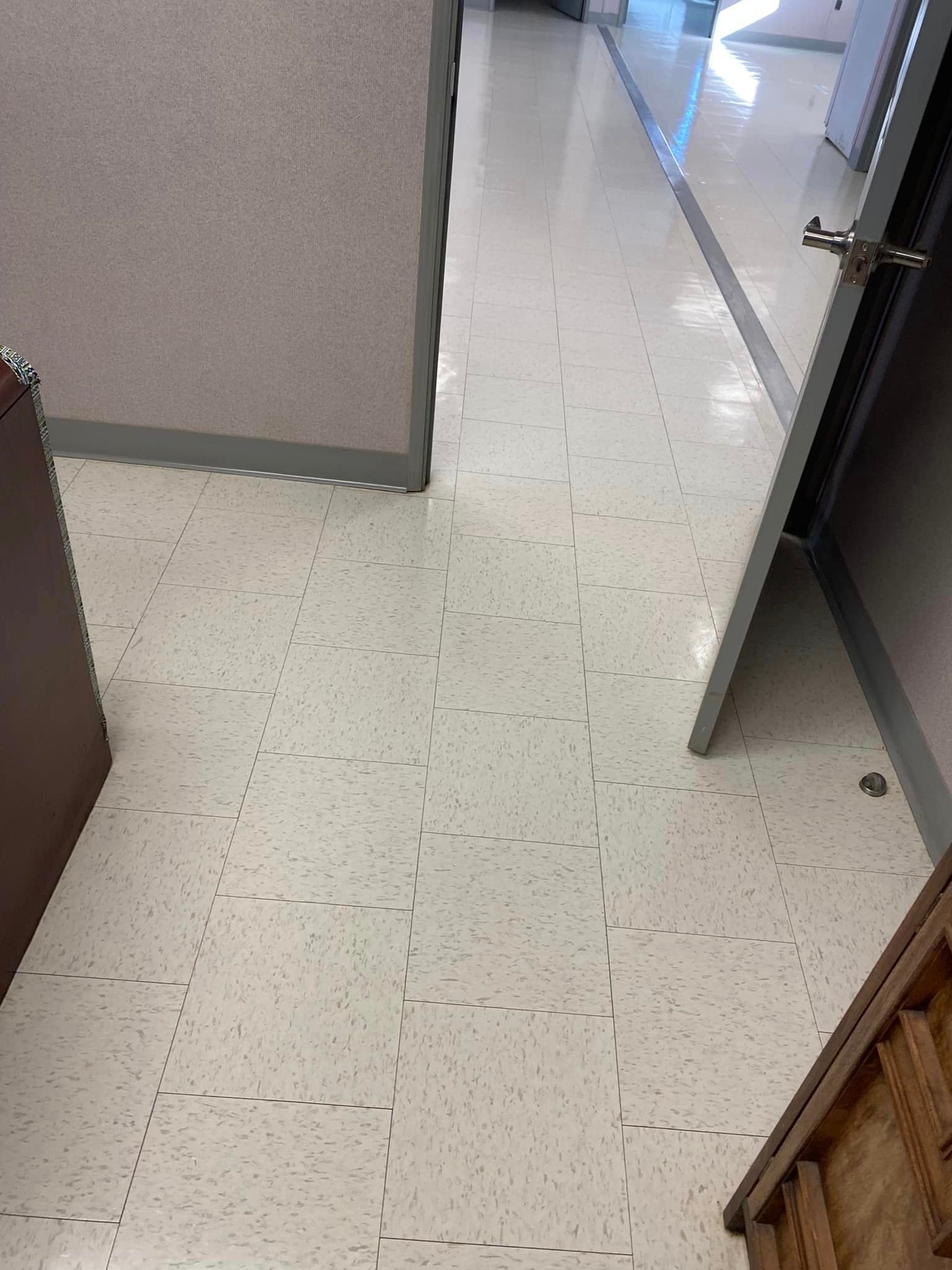A hallway with a white tile floor and a door.