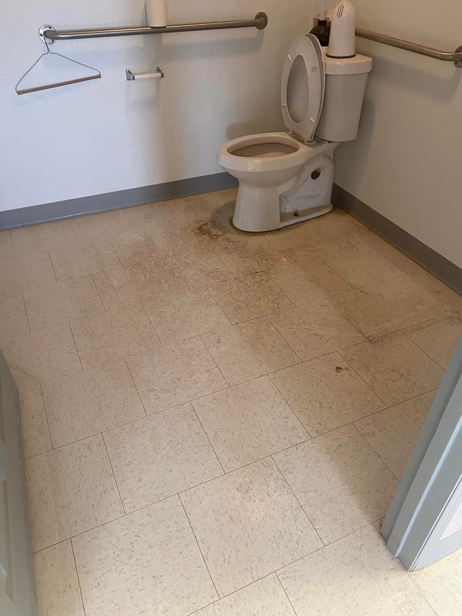A toilet is sitting on a tiled floor in a bathroom.