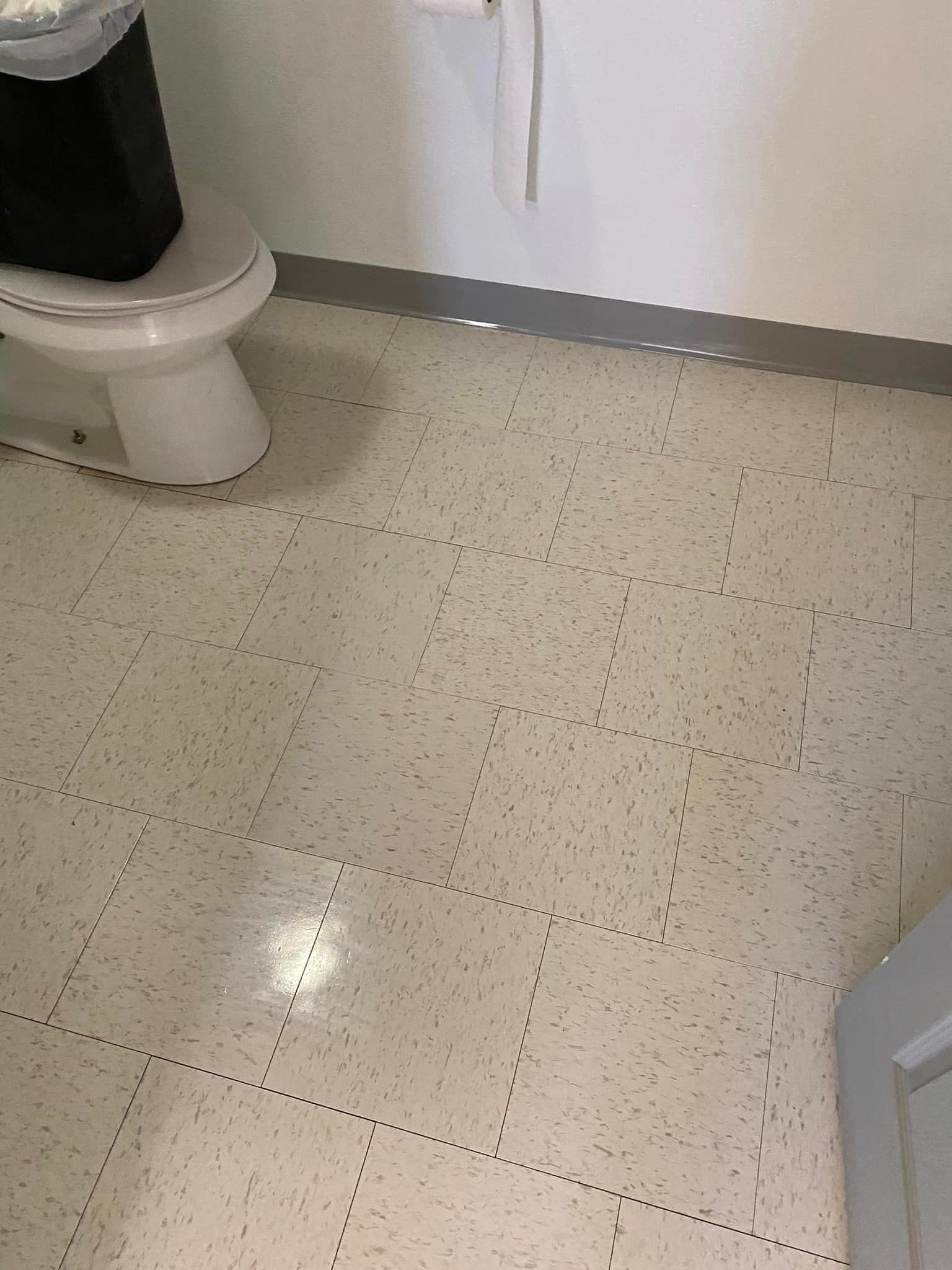A bathroom with a toilet and a trash can on the floor.