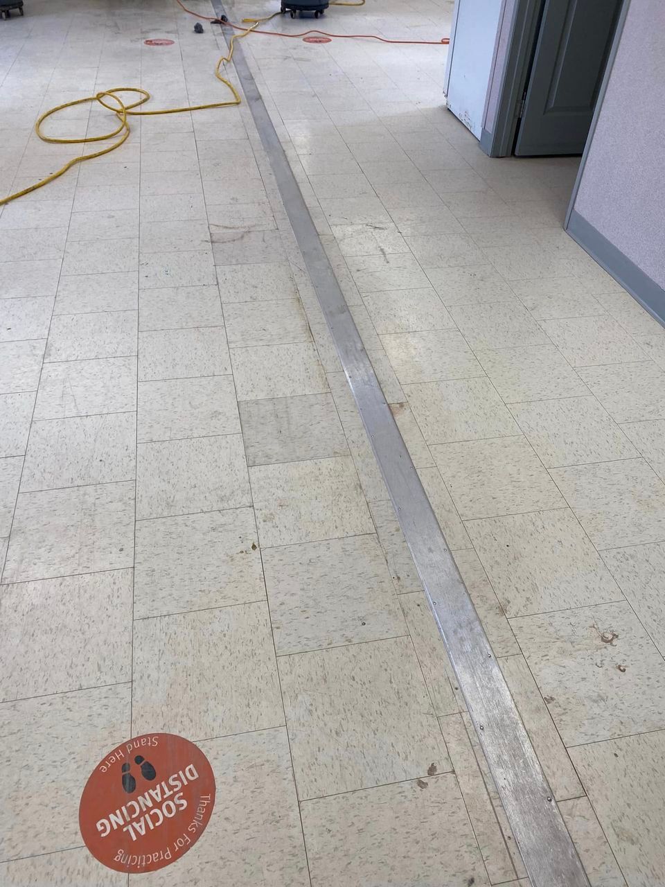 A tiled floor with a sticker on it that says `` social distancing ''.