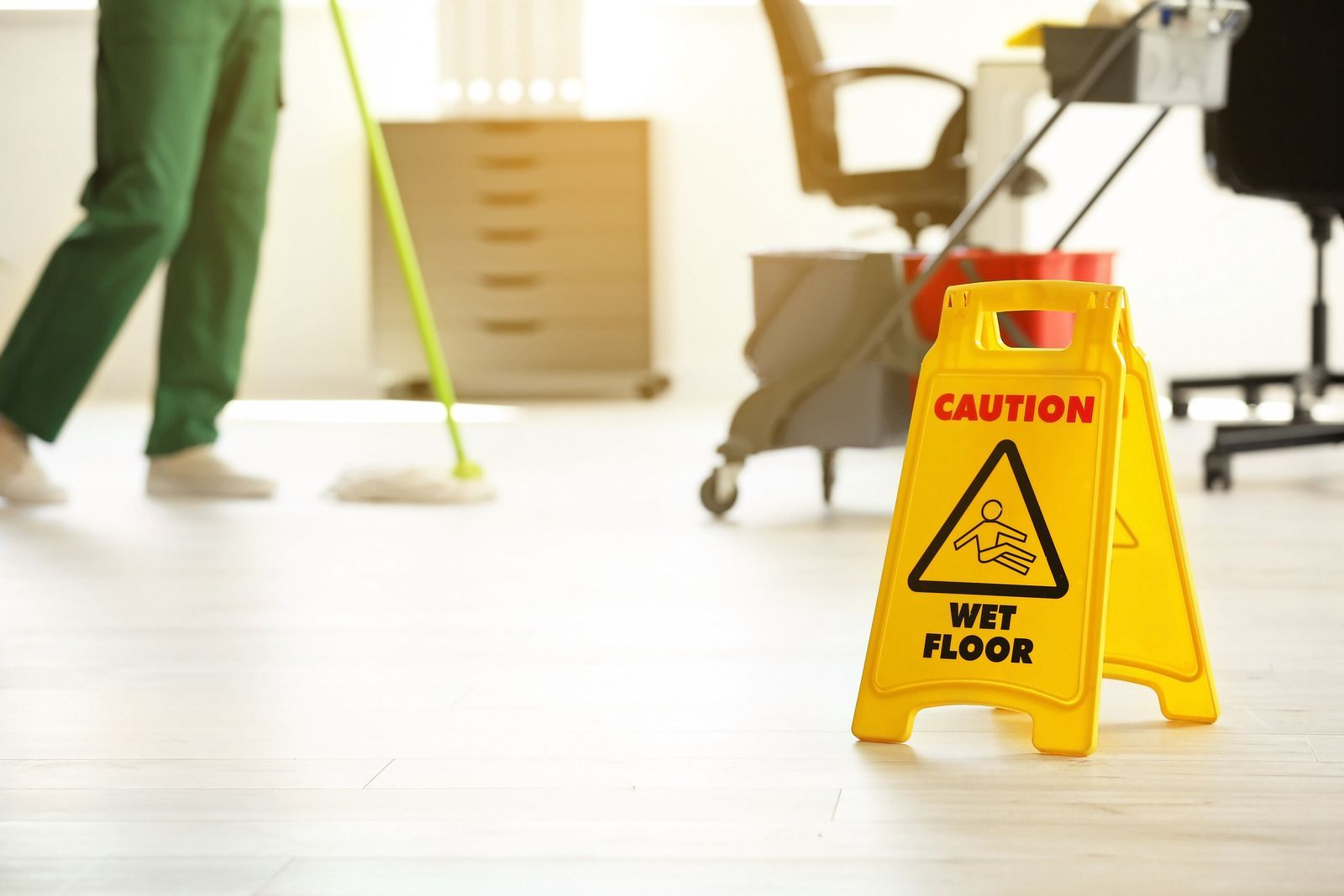 A person is mopping the floor next to a wet floor sign.