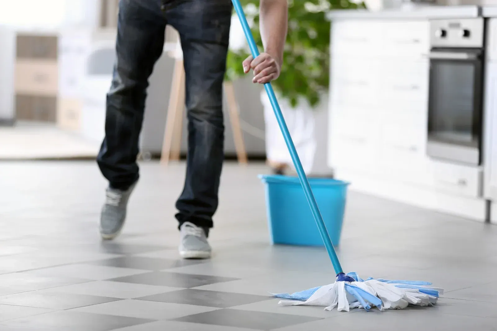 A man is cleaning the floor with a mop and bucket.