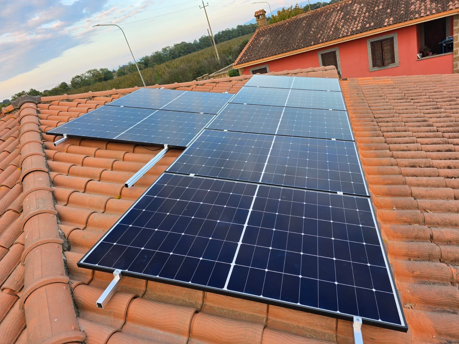 Pannelli solari installati sul tetto di tegole rosse di un edificio con l'esterno rosso.