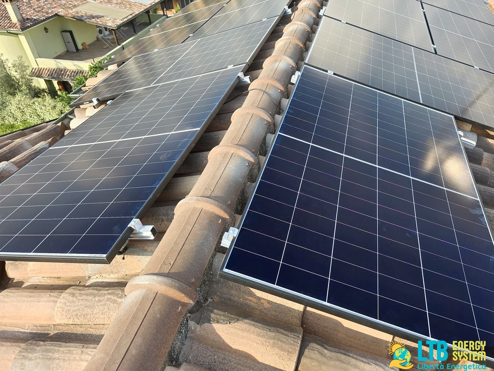 Pannelli solari installati su un tetto di tegole in terracotta in un ambiente esterno, che riflettono la luce del sole.