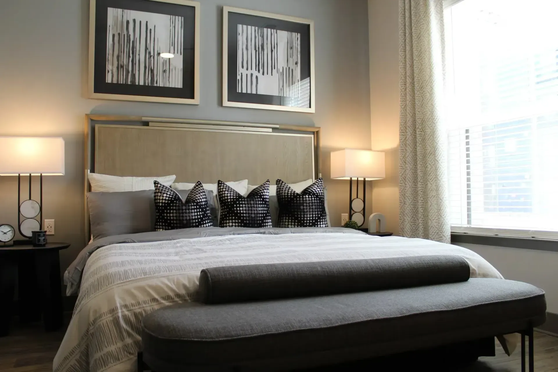 Bedroom with a large bed, two nightstands, lamps, and framed black-and-white art in neutral tones.